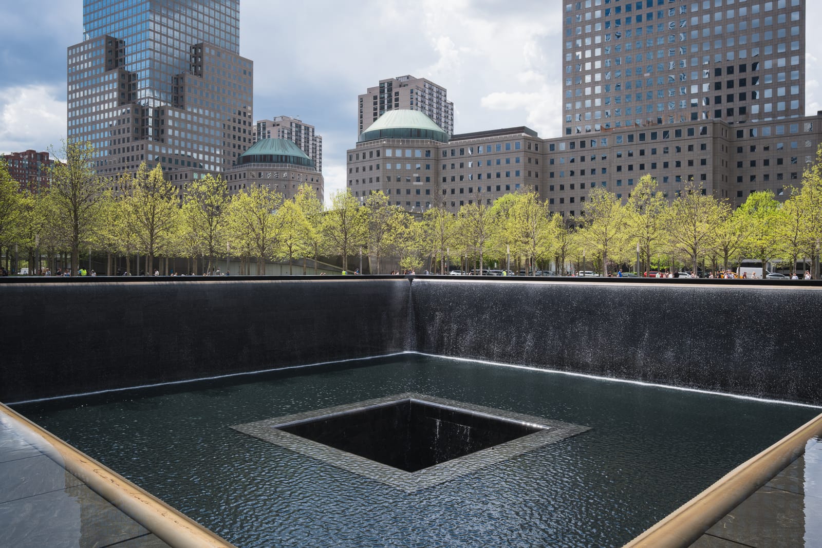 The north reflecting pool of the 9/11 Memorial in Lower Manhattan, with trees and office towers behind it